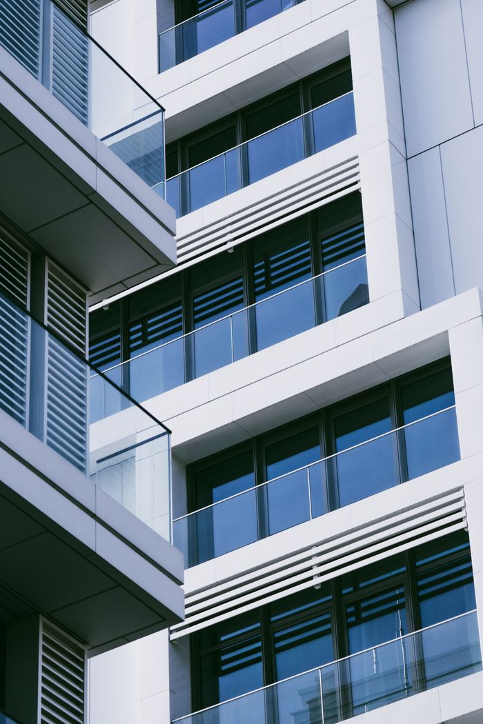 Hakkımızda Contemporary urban apartment building facade with glass balconies and geometric design.